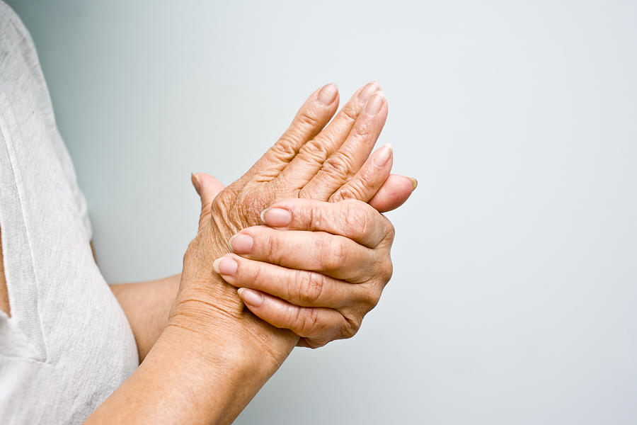 Elderly woman grasping arthritic hands Photograph by Michellegibson