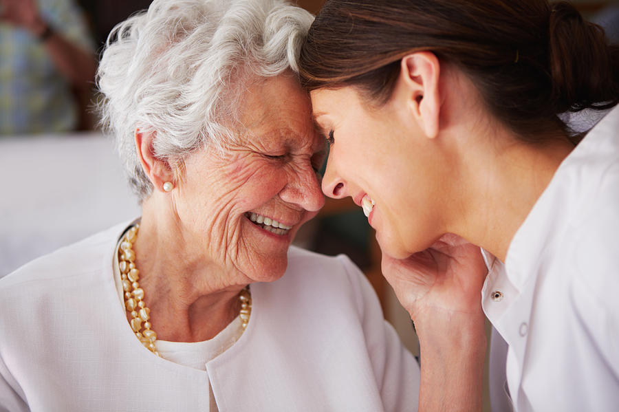 Elderly woman touching face of young female nurse Photograph by Squaredpixels