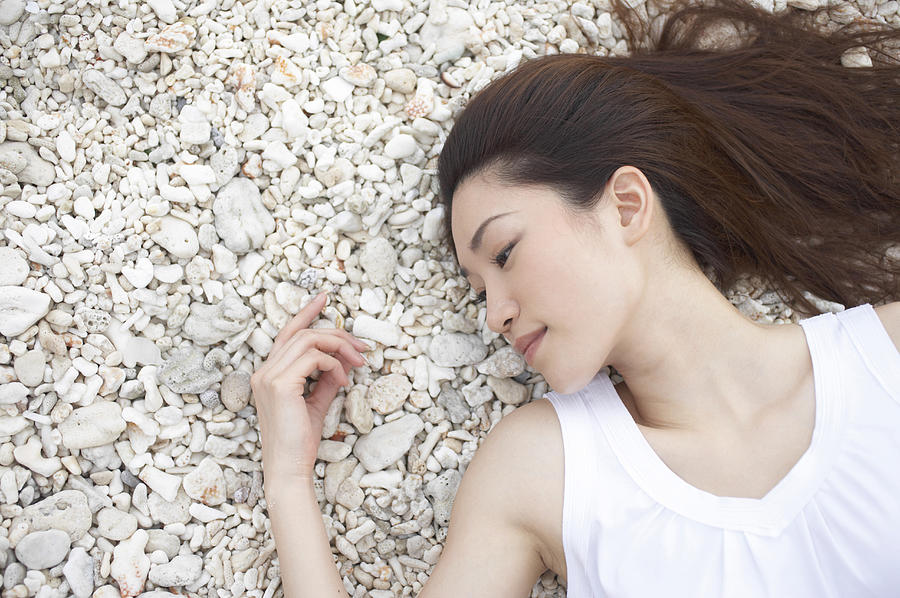 Elevated View of a Woman Lying on Pebbles With Her Eyes Closed Photograph by Dex