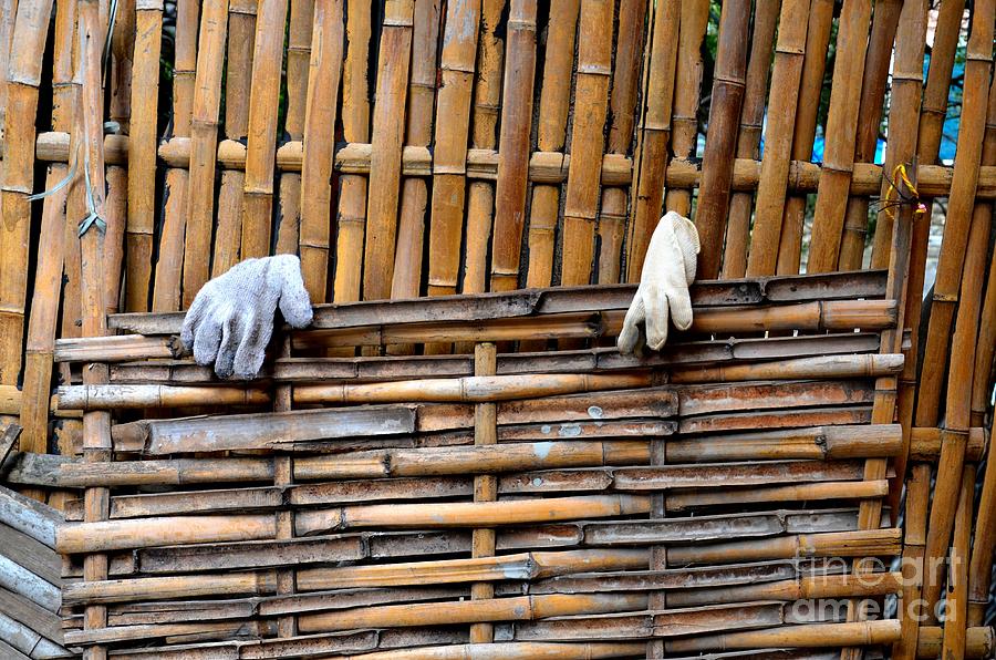 Empty gloves hanging on bamboo stick fence Photograph by Imran Ahmed