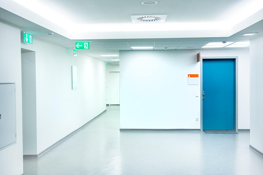 Empty white Hospital corridor with a blue door Photograph by Deepblue4you