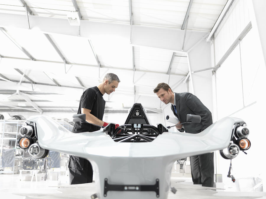 Engineer and automotive designer inspecting part-built supercar in car factory Photograph by Monty Rakusen