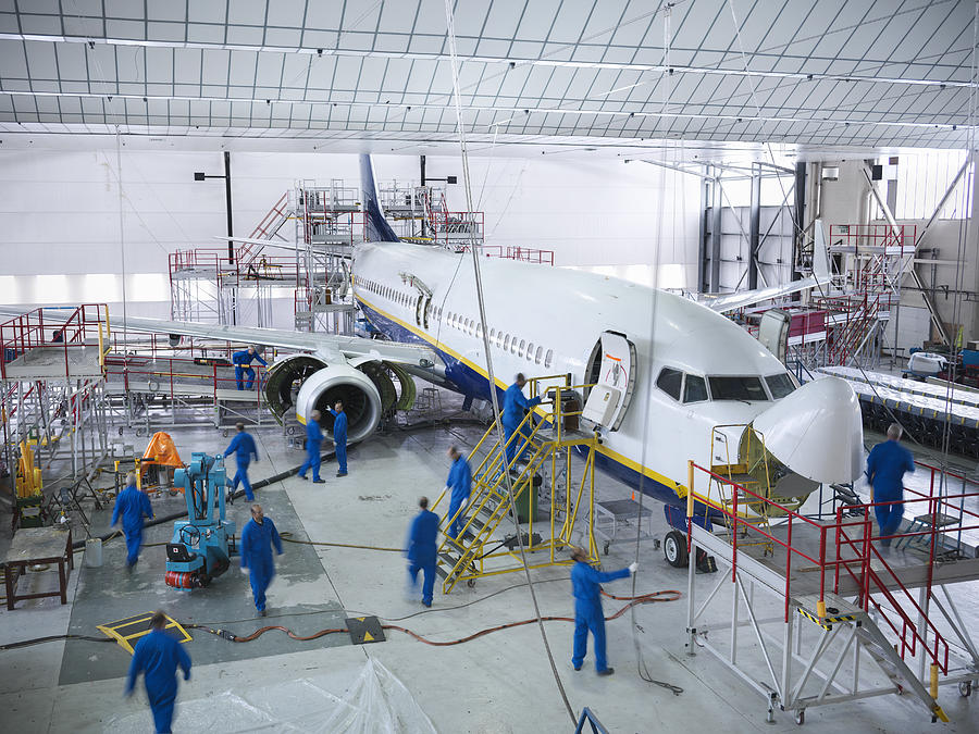 Engineers working with aircraft in repair hangar Photograph by Monty Rakusen