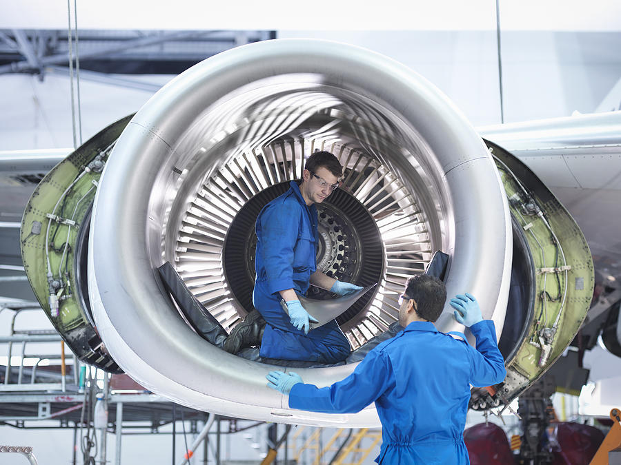 Engineers working with jet engine turbine blade in aircraft maintenance factory Photograph by Monty Rakusen