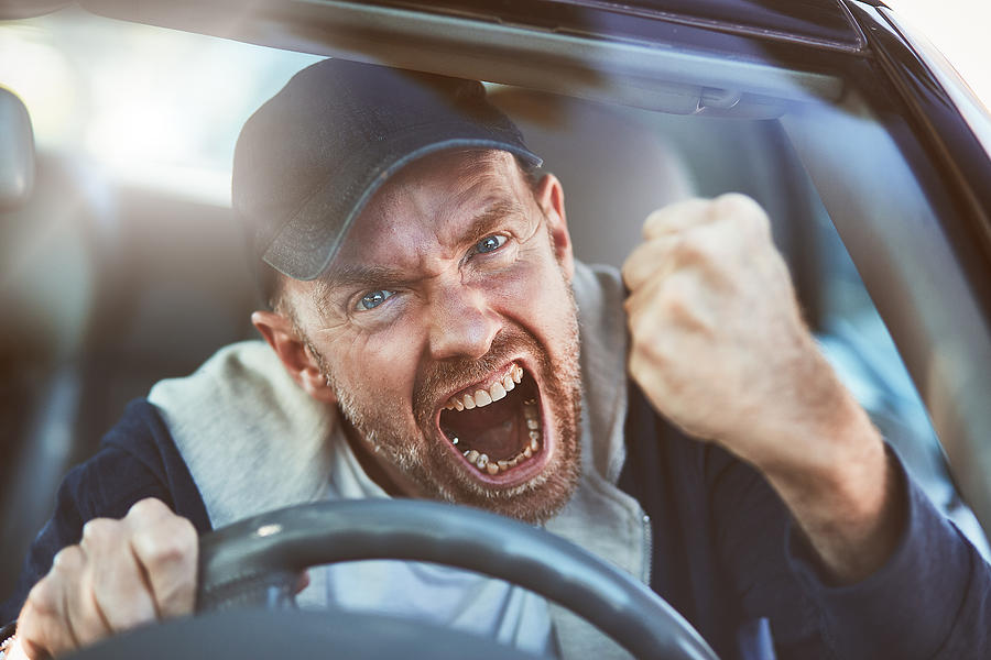 Enraged man shaking fist through windscreen: road rage Photograph by RapidEye