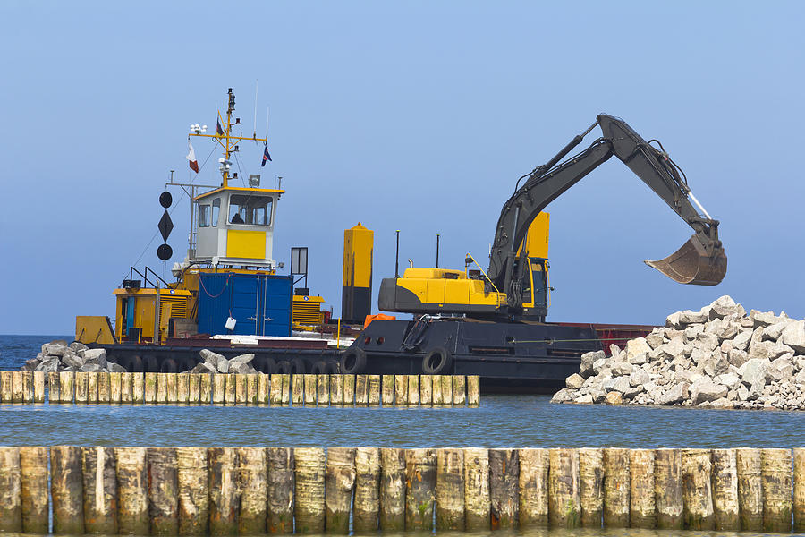 Excavator in a pier construction site Photograph by ewg3D