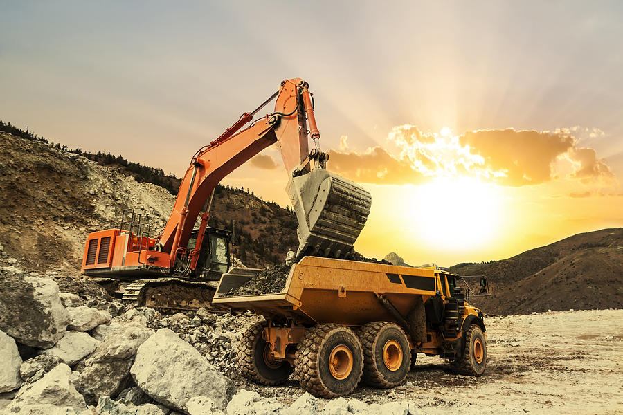 Excavator loading dumper truck on mining site Photograph by Guvendemir