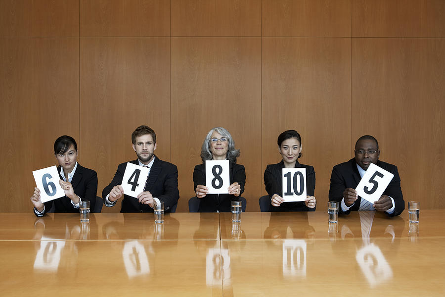 Executives at conference table holding score cards, portrait Photograph by Noel Hendrickson