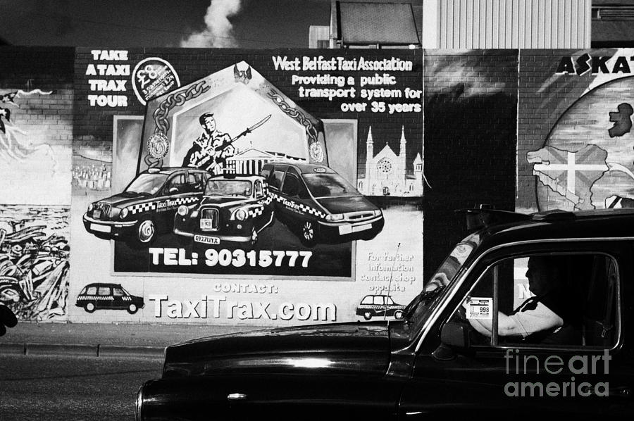City Photograph - Falls road black taxi driving past the International wall murals in the republican falls road area of west belfast Northern Ireland by Joe Fox