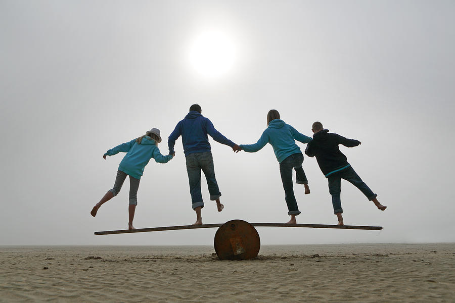 Family Balancing On Beach Photograph by Peter Cade