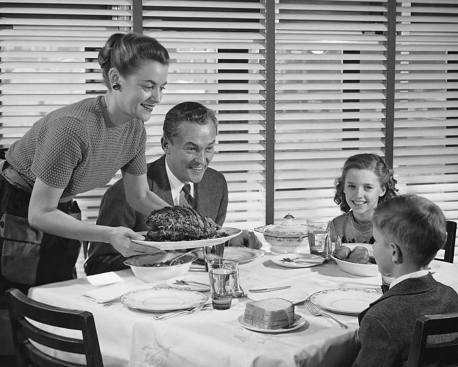 Family dinner, mother holding platter with roast on it Photograph by Stockbyte