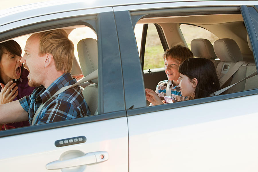 Family driving in car, parents shouting at children Photograph by Image Source