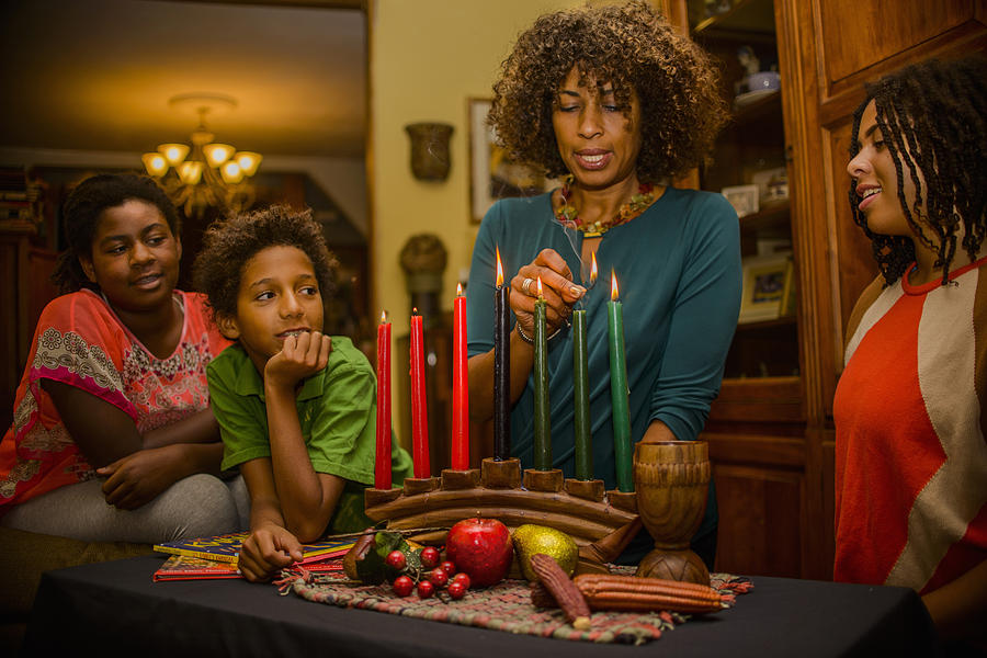 Family lighting kinara candles, celebrating Kwanzaa Photograph by Sue Barr