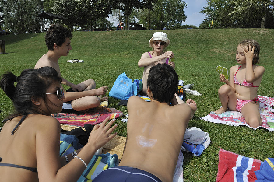 Family playing cards at beach, lying on grass Photograph by Sami Sarkis