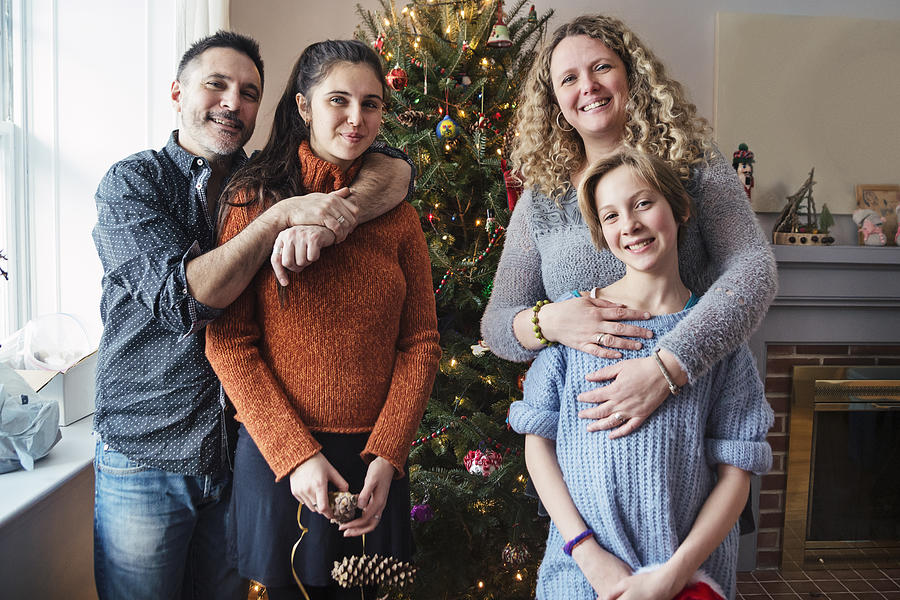 Family portrait in front of Christmas tree at home. Photograph by Martinedoucet