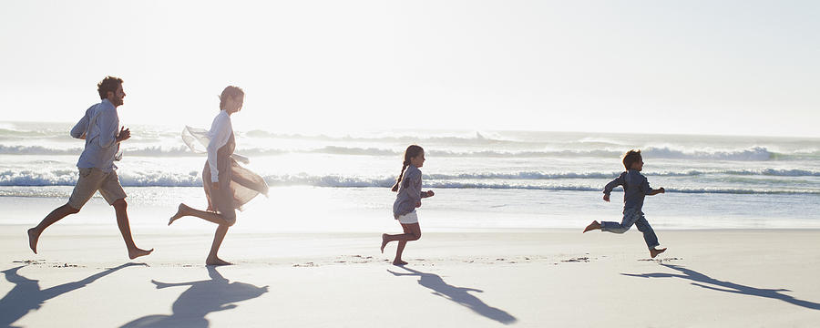 Family running on sunny beach Photograph by Sam Edwards