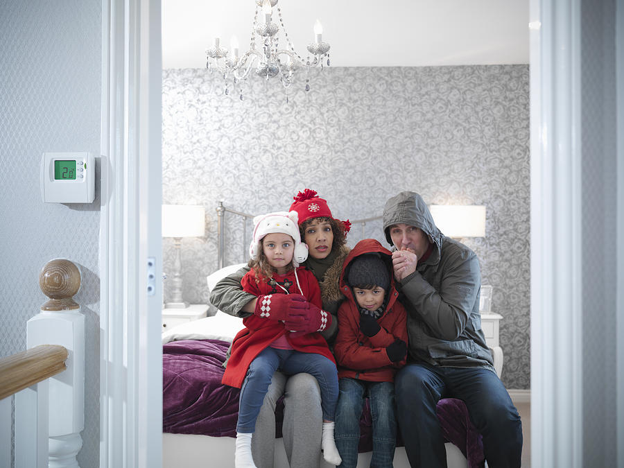Family wearing winter clothing in bedroom of energy efficient house Photograph by Monty Rakusen