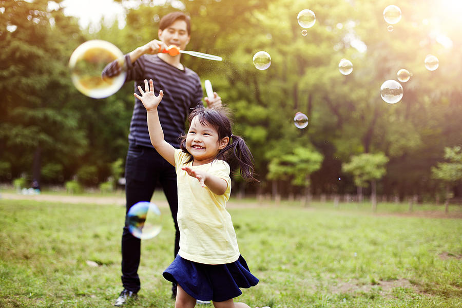 Father and daughter having fun in park with Soap Bubbles Photograph by Eli_asenova