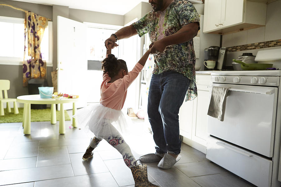 Father and daughter jiving in kitchen Photograph by Biz Jones