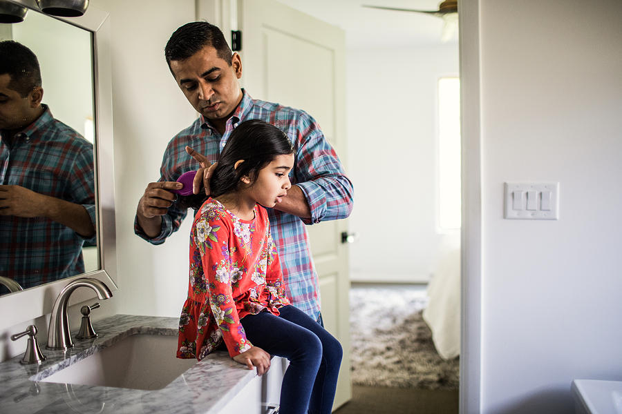 Father brushing daughters hair in bathroom Photograph by MoMo Productions