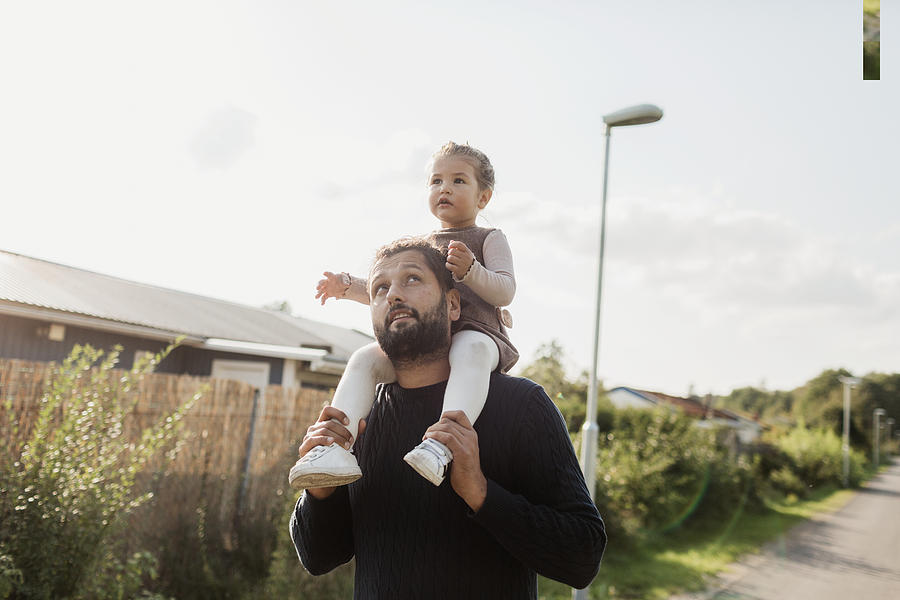 Father carrying daughter on shoulders Photograph by Johner Images