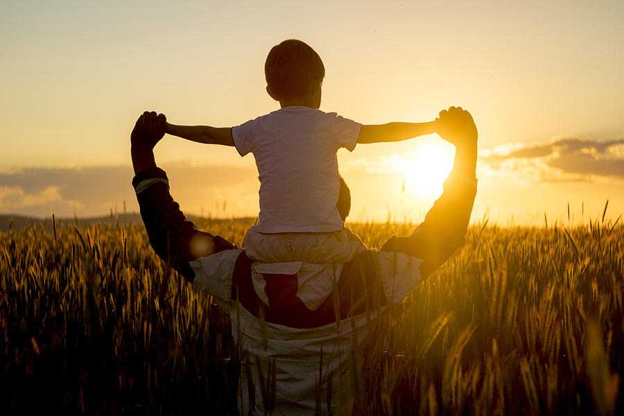 Father carrying son on shoulders in field of wheat at sunset Photograph by Aliyev Alexei Sergeevich
