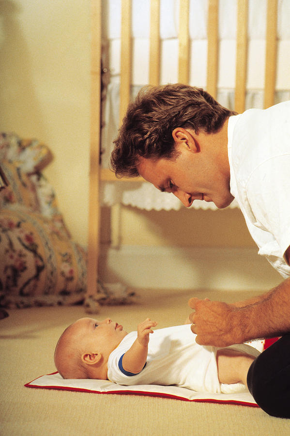 Father changing babys diaper Photograph by Comstock