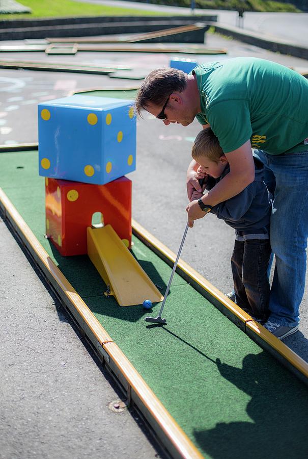 Outdoors Photograph - Father Helping Son To Play Mini Golf by Samuel Ashfield