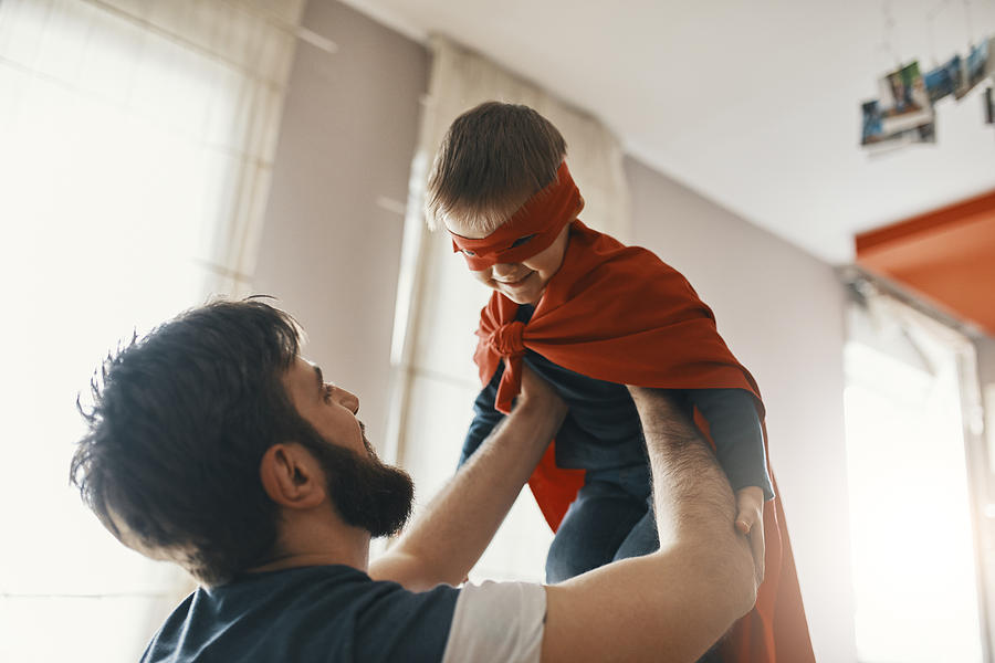 Father playing with his little son dressed up as a superhero Photograph by Westend61
