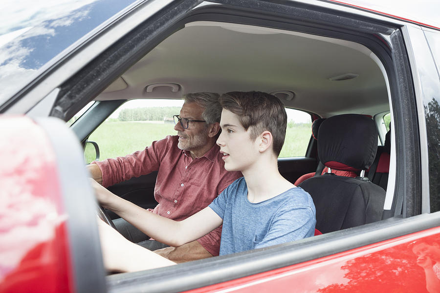 Father teaching son driving a car Photograph by Westend61