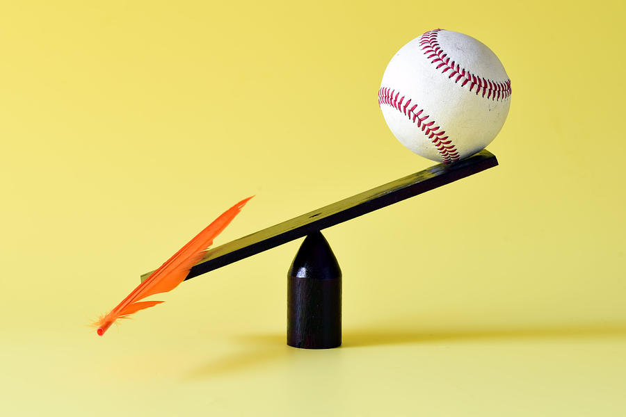 Feather and baseball on scale Photograph by Photo by Cathy Scola