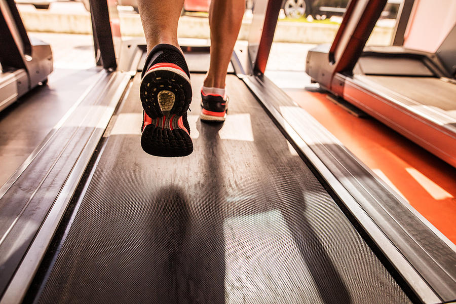 Feet of a runner on treadmill in a gym. Photograph by Skynesher