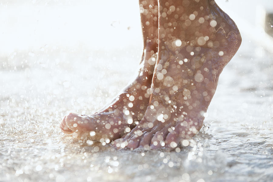 Feet under shower outdoors Photograph by PhotoAlto/Odilon Dimier