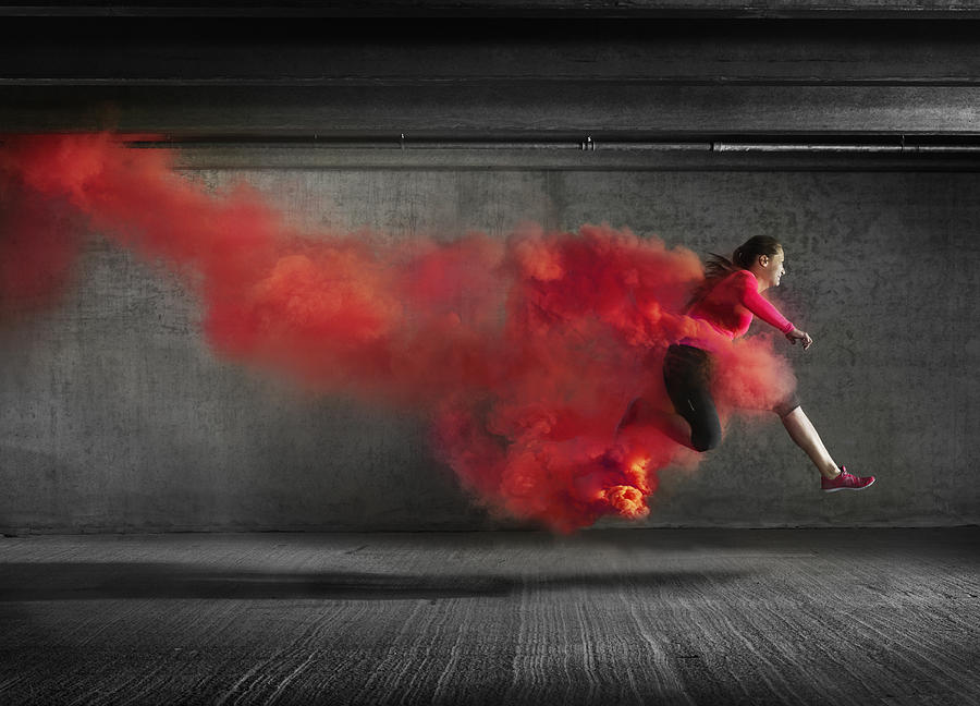 Female athlete leaping through smoke Photograph by Henrik Sorensen