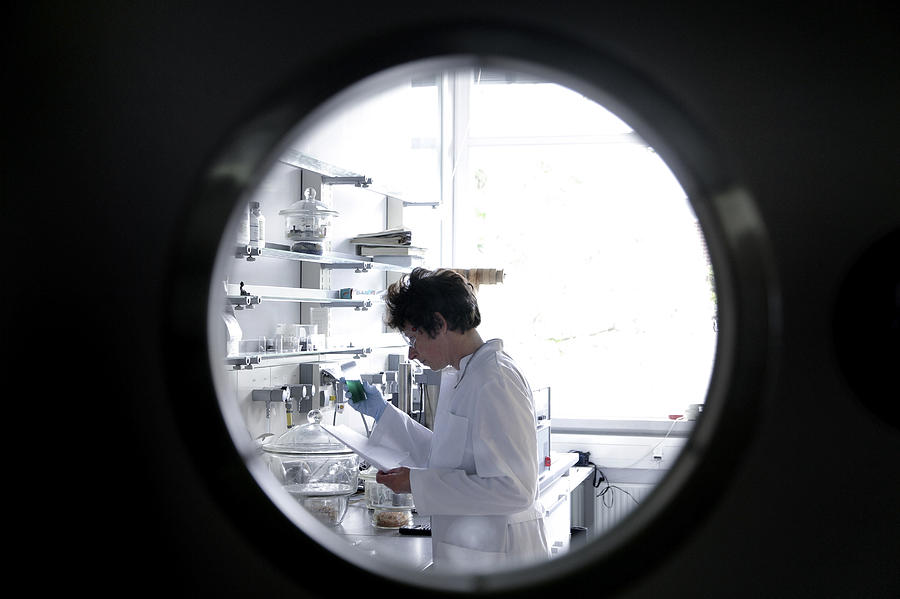 Female chemist working in lab watched through spy hole Photograph by Westend61