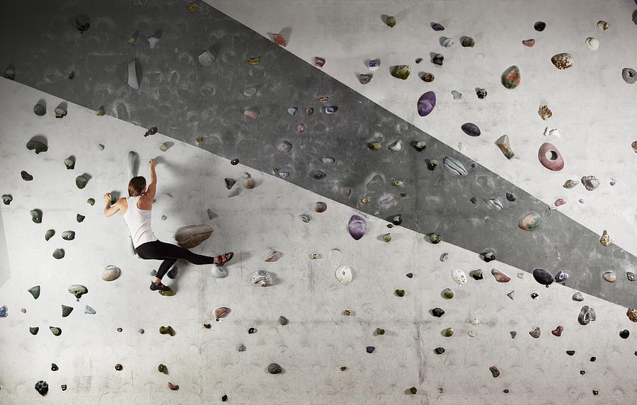 Female climber clinging to climbing wall Photograph by Robert Decelis Ltd