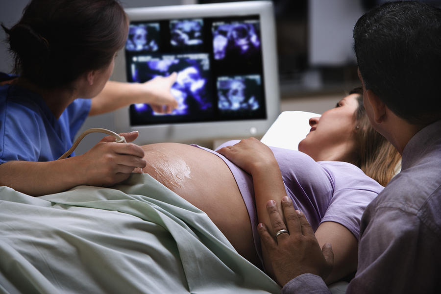 Female doctor pointing to ultrasound picture with pregnant woman Photograph by Jose Luis Pelaez Inc