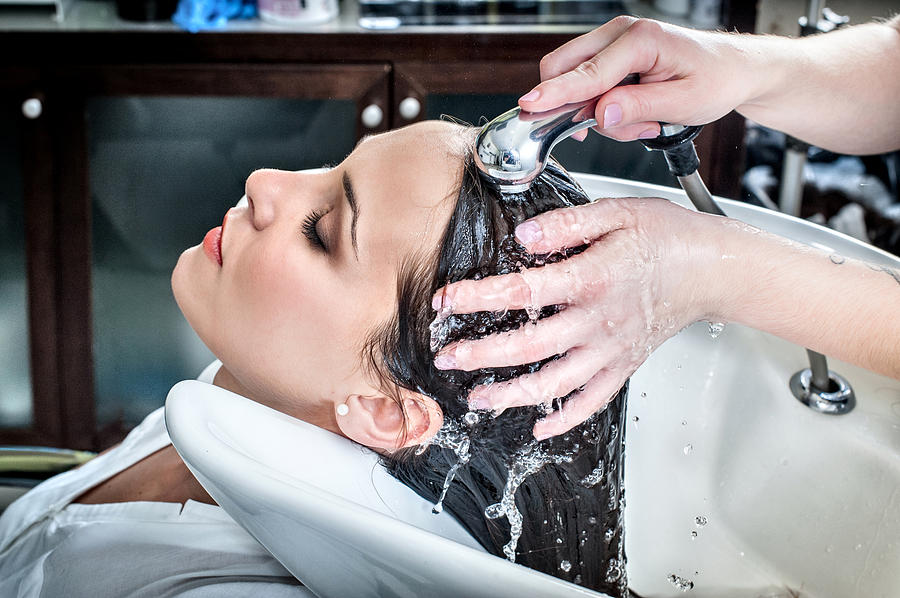 Female hairdresser rinsing young womans hair in hair salon Photograph by Stefano Oppo