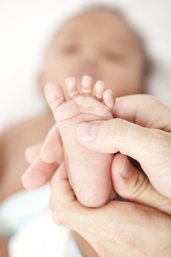 Female hands giving a massage to a newborns foot Photograph by RuslanDashinsky