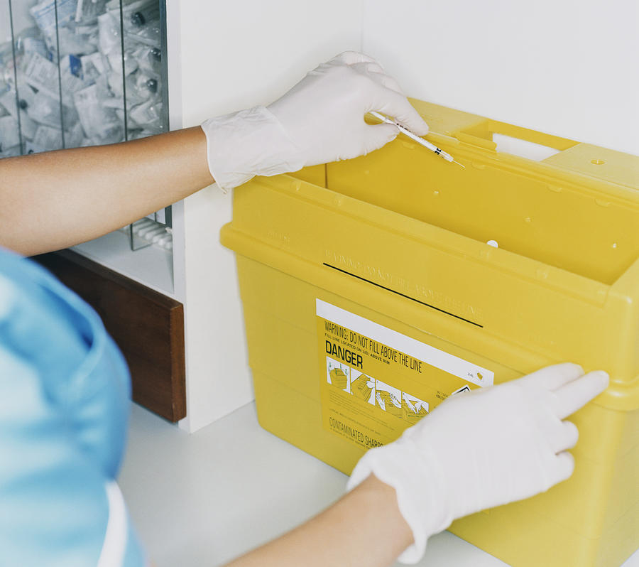 Female Nurse Disposing of a Syringe in a Waste Box Photograph by Janie Airey