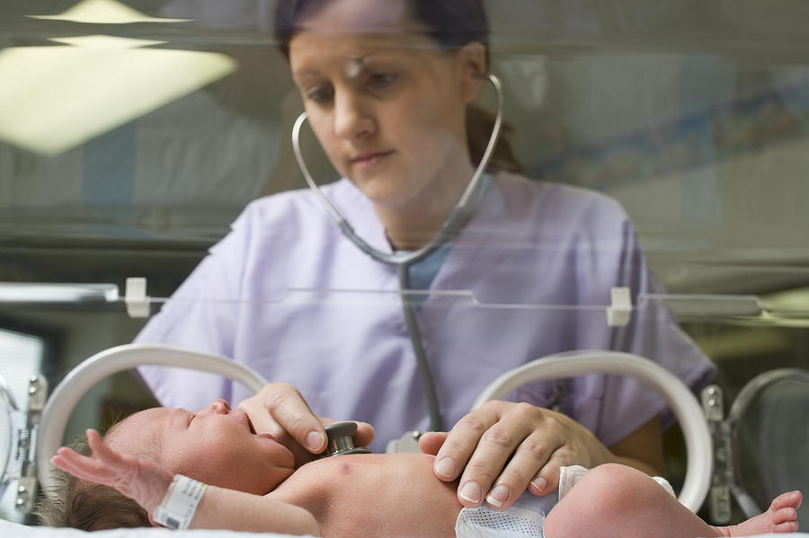Female nurse examining a newborn baby with a stethoscope Photograph by Rubberball