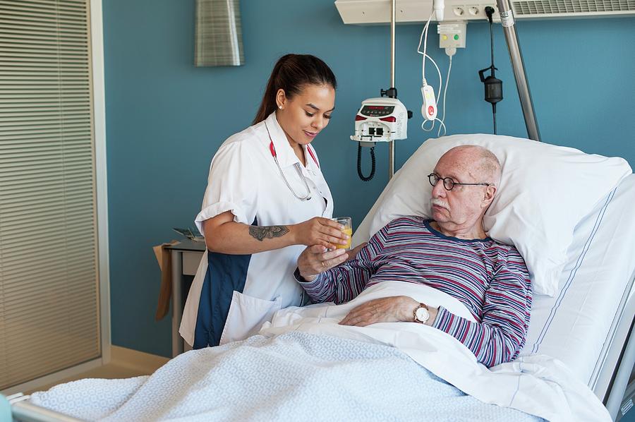 Female Nurse Giving Male Patient Fruit Juice Photograph By Arno Massee