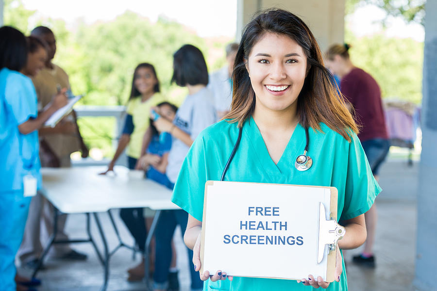 Female nurse holds Free Health Screenings sign at health fair Photograph by SDI Productions