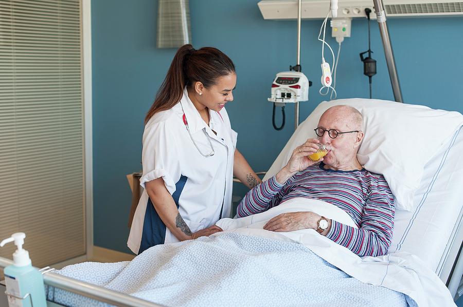 Female Nurse With Male Patient Drinking Juice Photograph By Arno Massee