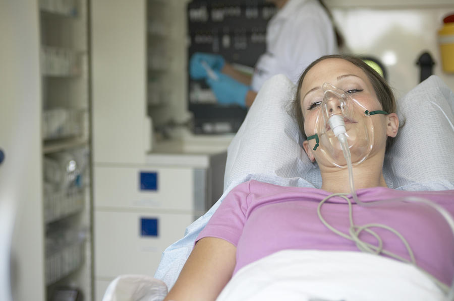 Female patient in ambulance, wearing oxygen mask, eyes open Photograph by Jochen Sand