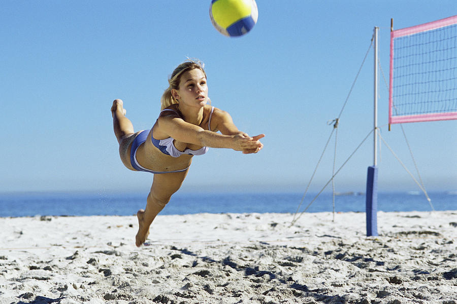 Female playing beach volleyball, diving to catch ball Photograph by PhotoAlto/Teo Lannie