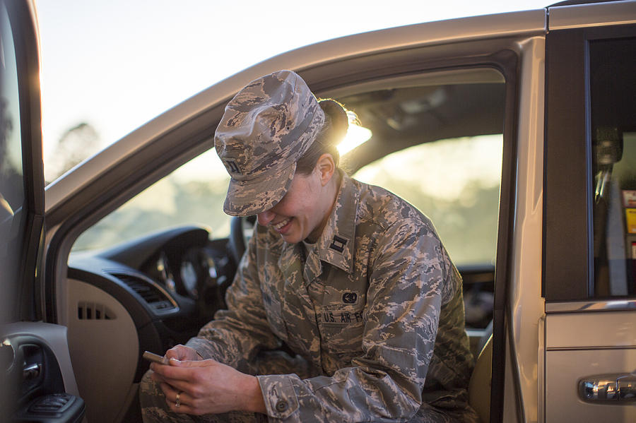 Female soldier sitting in car texting on smartphone at air force military base Photograph by Sean Murphy