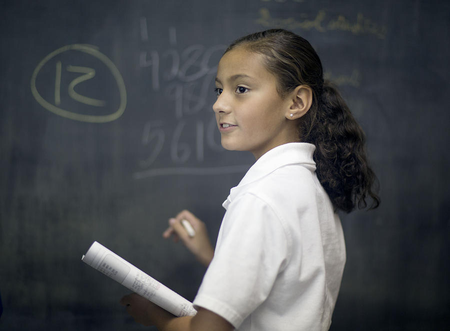 Fifth grade girl at chalk board. Photograph by Jonathan Kirn