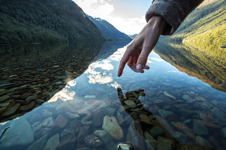 Finger touches surface of mountain lake, New Zealand Photograph by Swissmediavision