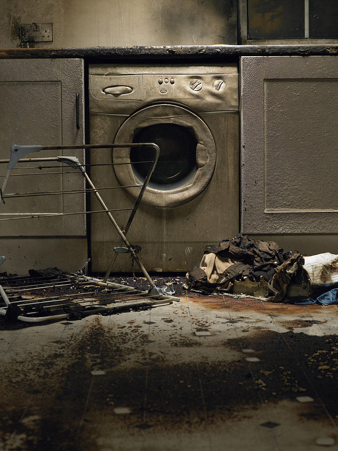 Fire damaged kitchen with washing machine and upturned clothes horse Photograph by Michael Blann